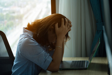 A man sitting down, his face unsettled. At the computer desk He has headaches and stress. Cause of hard work and insufficient rest.