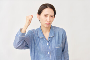 パジャマ姿の女性　拳を握って怒る　白背景