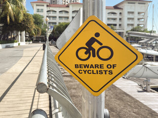 Yellow warning sign for cyclists near marina in Penang Malaysia highlighting safety for pedestrians