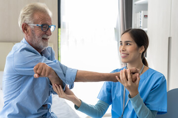 Female caregiver helping elderly Caucasian man doing exercise in senior home care