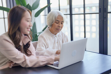 Young Asian Woman Helping Grandmother For Using new laptop