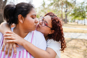 Young hispanic lesbian couple kissing in the park