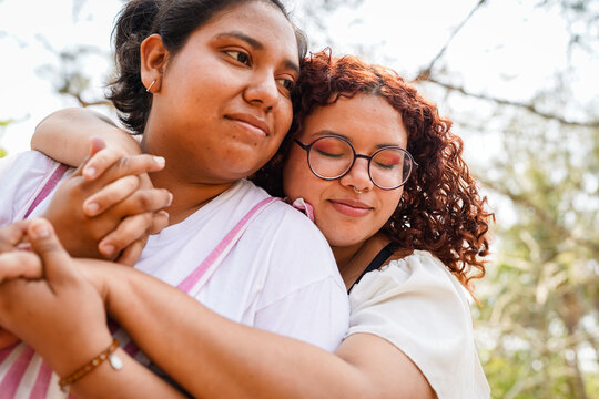 Two latin women embracing and holding hands in a park