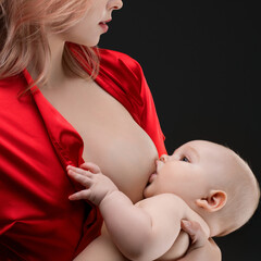 Mother nursing her baby while wearing a vibrant red robe in a dark setting
