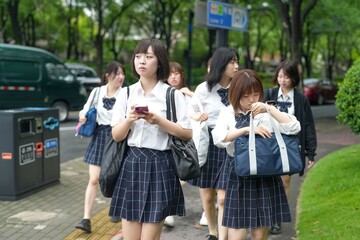 In early June in Pudong, Shanghai, seven Japanese high school girls in summer uniforms walk...