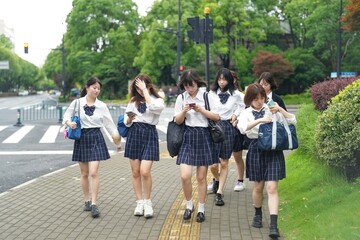 In early June in Pudong, Shanghai, seven Japanese high school girls in summer uniforms walk...