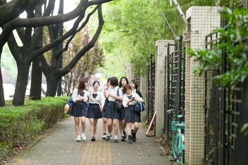 In early June in Pudong, Shanghai, seven Japanese high school girls in summer uniforms walk...