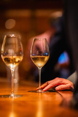 closeup-white-wine-glass-wood-bar-hand