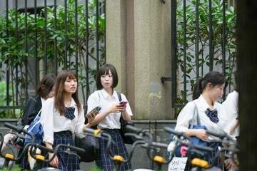 In early June in Pudong, Shanghai, seven Japanese high school girls in summer uniforms walk...