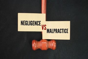 Judge's gavel and colored paper with the words negligence vs malpractice
