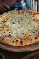 Delicious pizza with different types of cheese on a close-up wooden stand. Cheese pizza with crispy sides