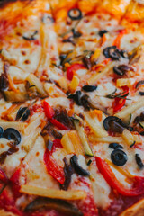 Pizza topping with vegetables and olives close-up. Appetizing pizza with cheese. Eating pattern view from above. Concept of delicious pizza and delivery of Italian cuisine