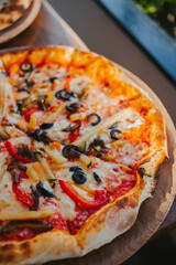Pizza topping with vegetables and olives close-up. Appetizing pizza with cheese. Eating pattern view from above. Concept of delicious pizza and delivery of Italian cuisine