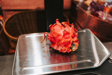 Red pitahaya on the scales in a supermarket. Weighing fruits before buying. Exotic fruits in the store