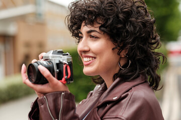 Young photographer smiling and taking photos outdoors with vintage camera