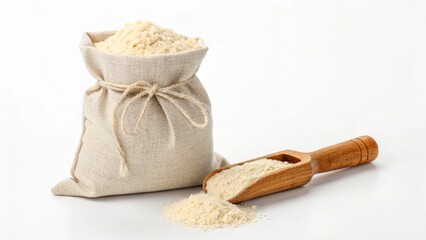 A natural linen sack, loosely tied, stands upright and brimful with light-colored flour, accompanied by a wooden scoop and a small mound of flour spilling on a clean white surface