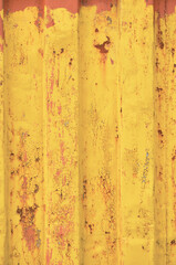 Yellow grunge sea freight container background, rusty corrugated pattern, red primer coating, vertical rusted steel, grungy paint detail, old aged weathered textured rust metallic copy space closeup