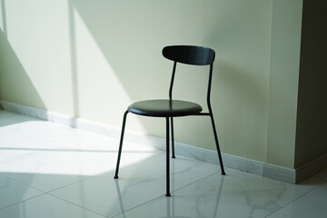 Minimalist Black Chair Against Light Green Wall with Sunlit Tile Floor in Modern Room