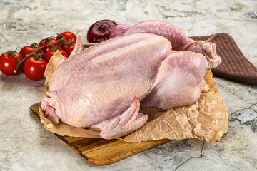 Fresh whole raw chicken over board