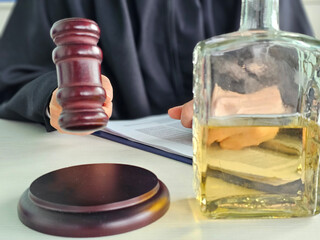 Judge holding gavel near a bottle of liquor during an unusual courtroom discussion concept