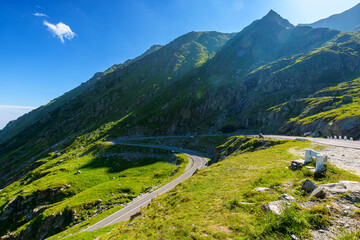 romania travel landscape with road in summer. memorable journey through transylvania alps scenery in morning light. touristic destination of europe. sunny day with blue sky and fluffy clouds