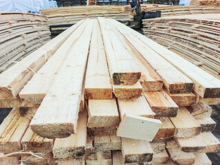 Boards and lumber are stacked in the open air.