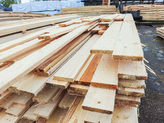 Boards and lumber are stacked in the open air.