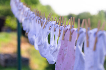 Close-up of freshly washed baby socks in pastel colors hanging outdoors on a clothesline with...