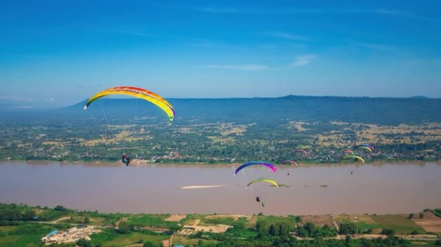 soaring adventure in the Sky: A vibrant collection of paragliders dance against a bright blue sky, creating a scene of airborne freedom above the expansive landscape.