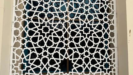 White Geometric Islamic Pattern Window Screen with Star Design against Dark Glass Background