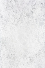 Bubbles create a textured appearance on a surface during a cleaning process in bright lighting