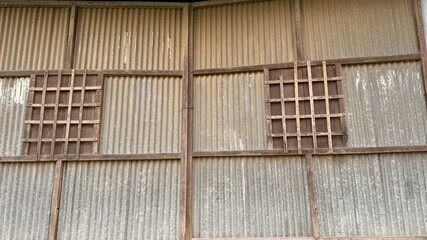 Corrugated Metal Wall with Framed Square Openings and Rustic Wooden Grids Overlays