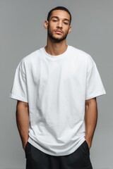 A young man with medium-dark skin tone wears a plain white t-shirt, posing confidently against a neutral gray background. Ideal for fashion, clothing mockups, or modern branding visuals.