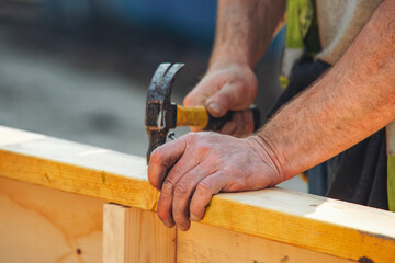 Close-up of hands of builder joiner using plywood and timber to asseble shutter panel for concrete...