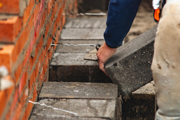 Construction worker laying concrete blocks on building site