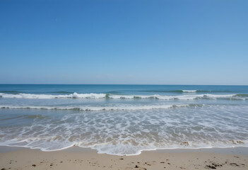 Calm Ocean Waves Gently Rolling onto the Sandy Beach Shoreline Under a Clear Sky