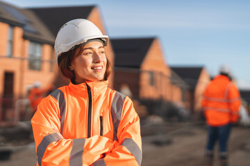 Portrait of Young female Construction works superviser overseeing building site activities  during sunny day while holding project files and wearing safety gear © Iryna