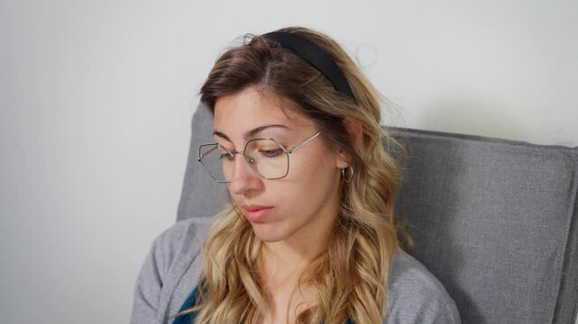 Young woman shakes head, looking down with disbelief in quiet indoor setting
