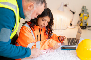 Construction project manager and architect collaborating to discuss blueprints drawings and plans at workspace office