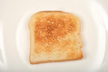 Close-up, top-down shot features a single slice of golden-brown toast centered on a plain white surface.