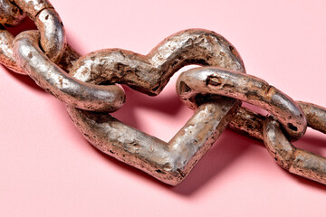 Obraz premium A unique heart-shaped chain links symbolize love and connection against a vibrant pink background, blending strength with emotion.