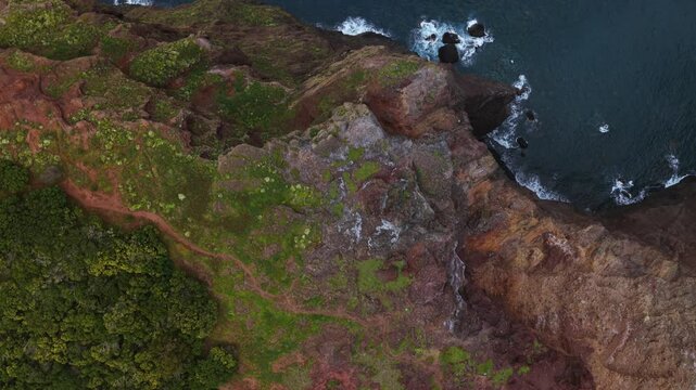 Aerial view of the steep cliffs of Calhau da Furna do Bode plunging into the deep blue Atlantic ocean, showcasing the raw beauty of Madeira Island's coastline