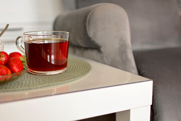 filiżanka herbaty na stoliku kawowym obok wygodnego fotela, chwila relaksu, a cup of tea on a coffee table next to a comfortable armchair, a moment of relaxation,