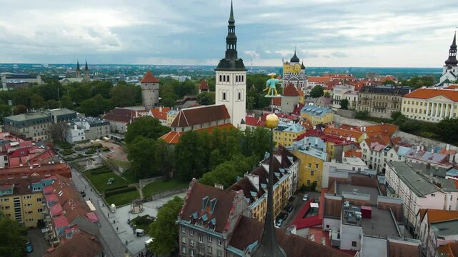 Gorgeous aerial drone footage spinning and orbiting around a historic little statue called Old Thomas on top of a high altitude church towern in Tallinn central city medieval old town or city.