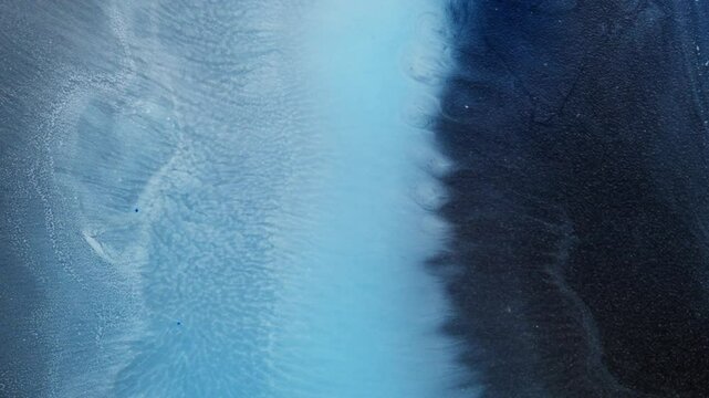 Black and blue alcoholic ink blend creates abstract textures in close-up macro view