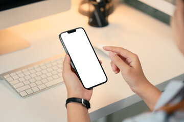 Close up of woman using a smartphone with blank screen at modern desk