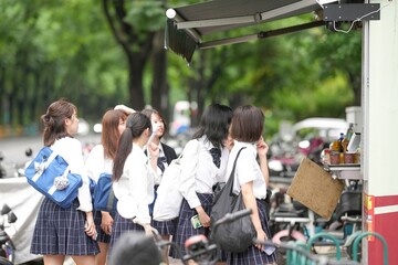 In early June, in Pudong, Shanghai, a group of Japanese high school girls dressed in summer uniforms are on their way to school along a city street, stopping by a food stall to buy something to eat.