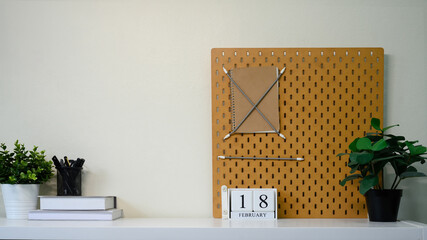 Obraz premium Creative home office decor with a pegboard, notebook, potted plants, and a calendar