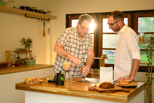 Senior man and son brewing fresh coffee together during a cozy morning at home. Father day concept