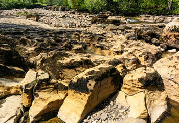 Intricate sandstone rock formations at Wain Wath Force in the Yorkshire Dales, England. Eroded shapes and pockets formed by centuries of water flow are visible during low water levels in summer